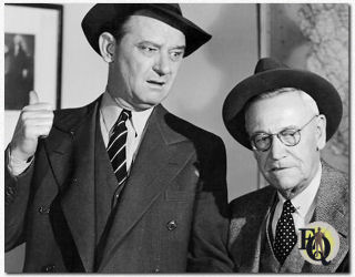 Sergeant Velie (James Burke) legt één en ander uit aan Inspecteur Queen (Grapewin) in "A Close Call for Ellery Queen" (1942).
