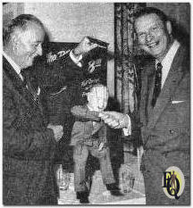 A Puppet likeness of Raymond F. Sullivan (L), president, Sullivan, Stauffer, Colwell & Bayles, is introduced to radio-TV-announcer Ernest Chappell. The puppet was created by the SSC&B art staff and presided over the agency's recent eighth anniversary festivities.