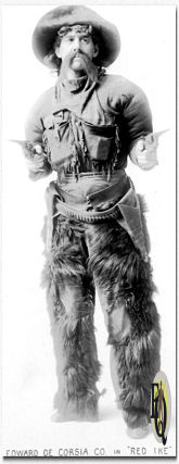 Stage still from the vaudeville play "Red Ike" starring Edward de Corsia and Company. Edward de Corsia is posed with fur lined chapped and two drawn six guns to go with the rest of his cowboy attire. (Photograph by Baker Art Gallery, Columbus, Ohio)