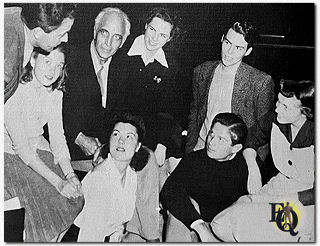 Mr. Lieber gives the cast a few directions before a rehearsal for the fall play "Kind Lady". Barbara East, Barbara Clark, Fritz Lieber Sr., Mary Jean Copeland, Gene White, George Nader (center, sitting with dark sweater), Charlotte Clary, Betty Leigh Van Werden, Betty Ely, Barbara Kennedy, De De Harvey. Mr. Lieber Sr. was on hand with veteran suggestions. (1942)