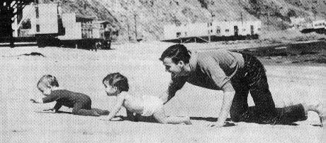 Jim kruipend over het strand met zijn éénjarige zoon Tim (vooraan) en dochter Heidi.