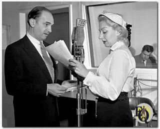 Zicht binnenin de radiostudio tijdens een uitvoering van City Hospital op CBS radio (1951-1958). Santos Ortega tegenover een onbekende tegenspeelster.
